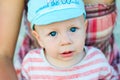 Close up of baby boy face with blue eyes with open mouth and blue cap. Child and children emotions Royalty Free Stock Photo