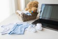 Close up of baby clothes, toys and laptop at home Royalty Free Stock Photo