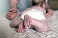 Close up of a baby feet. Mother`s hands in the foreground. Childcare concept. Selective focus