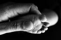 Close up baby feet in mother hands on a black background. Prevention of flat feet, development. Royalty Free Stock Photo
