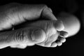 Close up baby feet in mother hands on a black background. Prevention of flat feet, development Royalty Free Stock Photo