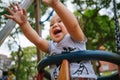 Close up of baby girl playing on outdoor playground swing. Toddler playing on school or kindergarten yard. Active kid on colorful Royalty Free Stock Photo