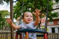 Close up of baby girl playing on outdoor playground swing. Toddler playing on school or kindergarten yard. Active kid on colorful Royalty Free Stock Photo