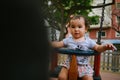 Close up of baby girl playing on outdoor playground swing. Toddler playing on school or kindergarten yard. Active kid on colorful Royalty Free Stock Photo