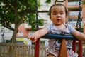 Close up of baby girl playing on outdoor playground swing. Toddler playing on school or kindergarten yard. Active kid on colorful Royalty Free Stock Photo