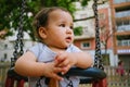 Close up of baby girl playing on outdoor playground swing. Toddler playing on school or kindergarten yard. Active kid on colorful Royalty Free Stock Photo