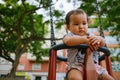 Close up of baby girl playing on outdoor playground swing. Toddler playing on school or kindergarten yard. Active kid on colorful Royalty Free Stock Photo