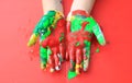 Close-up baby hands with colorful fingers painted over red background