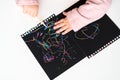 Close up of the hands of a little child drawing on magic scratch painting paper with drawing stick. Royalty Free Stock Photo