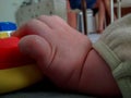 Close up of baby`s hand on play mat, holding colorful toy