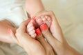 close up baby& x27;s tiny feet in paren& x27;t hands. parent holding newborn in arms. happy family