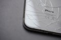 Close-up of the back cover of a smartphone with cracks and the inscription iPhone