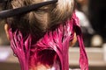 Close-up of the back of the head of the dyed strands of blond hair in a bright pink color, beauty salon