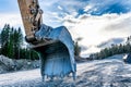 Close up back view at beautiful large excavator`s scoop on new not yet ready road. Sunny evening with dark blue clouds, spring Royalty Free Stock Photo