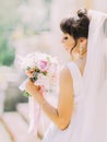 The close-up back view of the charming bride holding the wedding bouquet of colourful peonies.