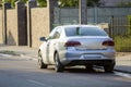 Close-up back view of new shiny expensive silver car moving along city street on blurred trees, cars and buildings background on Royalty Free Stock Photo