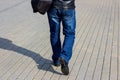 Close up back view of a pedestrian man in the jeans with the bag walking in the street. Royalty Free Stock Photo