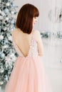 Close up back view portrait of beautiful young red haired woman in elegant pink dress, standing in front of decorated Royalty Free Stock Photo