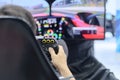 Back view and selective focus right hands of young man gamer who enjoying with racing game via gaming wheel controller Royalty Free Stock Photo