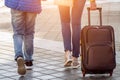 Close up back view of a teen and a woman holding suitcase baggage walking on the street in the sunny morning in the autumn Royalty Free Stock Photo