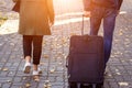 Close up back view of a woman and a man holding suitcase baggage walking on the street in the sunny morning in the autumn Royalty Free Stock Photo