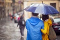 Close-up from back of a young couple in love who is walking the city on a rainy day. Walk, rain, city, relationship Royalty Free Stock Photo