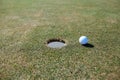 Close up background of golf ball next to hole on green grass Royalty Free Stock Photo