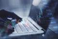 Close up of backlit female hands using laptop keyboard with growing forex chart on blurry background. Trade, finance and stock