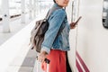 Close up of backpacker caucasian woman holding luggage at train station ready to catch the train. Holding mobile phone while using Royalty Free Stock Photo