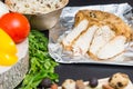 Close up of baked chicken breast on foil near vegetables and a p Royalty Free Stock Photo