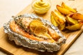 Tasty baked fish and fried potatoes on wooden cutting board