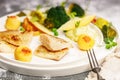 Close-up Baked sea fish fillet with vegetables. Tilapia fillet with broccoli, cherry tomatoes, fried potatoes, green peas Royalty Free Stock Photo