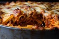 Close-up of a baked ziti pie, with crispy edges and layers of pasta, cheese, and meat, in a deep-dish baking pan