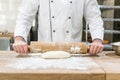 close up of baker hands rolling out raw dough Royalty Free Stock Photo