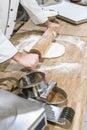 close up of baker hands rolling out uncooked dough Royalty Free Stock Photo