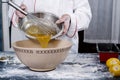 Close-up of a baker pouring mixture into a plastic bowl