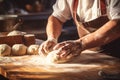 Close-up on baker\'s hands kneading a dough on a wooden table in bakery