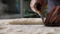 Baker dividing dough into pieces with knife in bakery kitchen Royalty Free Stock Photo