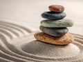 Close-up of a balanced stack of multicolored smooth stones arranged on raked sand with gentle curved lines creating a peaceful and Royalty Free Stock Photo
