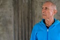 Close up of bald senior man thinking while wearing blue hoodie a Royalty Free Stock Photo