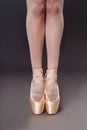 Close-up of Ballerine feet in pointe shoes on grey background. Ballerina is standing on the hips. Studio shot of ballerina legs in