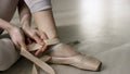 Close up for ballet dancer putting on, tying ballet shoes. Ballerina putting on her pointe shoes sitting on the floor. Royalty Free Stock Photo