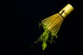 Close up bamboo whisk and matcha green tea powder on black background. Royalty Free Stock Photo