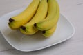 Close up of banana fruits is on a white porcelain plate on natural background