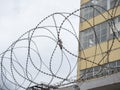 Close-up of the barbed wire on the fence. Building in the background. The concept of protecting borders from intrusion