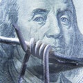 Close up barbed wire and US Dollar bill as symbol of economic warfare, sanctions and embargo busting