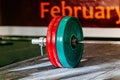 close-up barbell with red and green plates on wooden platform