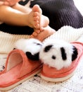 Close up bare foot in the morning at home, relaxing. Funny fluffy panda slippers. Comfort aesthetics style