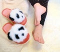 Close up bare foot in the morning at home, relaxing. Funny fluffy panda slippers. Comfort aesthetics style