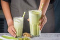 Close-up, barista girl`s hands are holding out a glass. Matcha green tea drink in a glass with a straw. Useful latte
